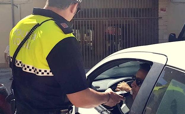 Un agente realiza una prueba de alcoholemia a un conductor.
