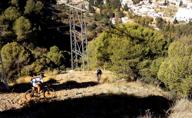 Ciclistas bajan habitualmente por las laderas de la colina de la Alhambra, en el Parque Periurbano Dehesa del Generalife, un área protegida.