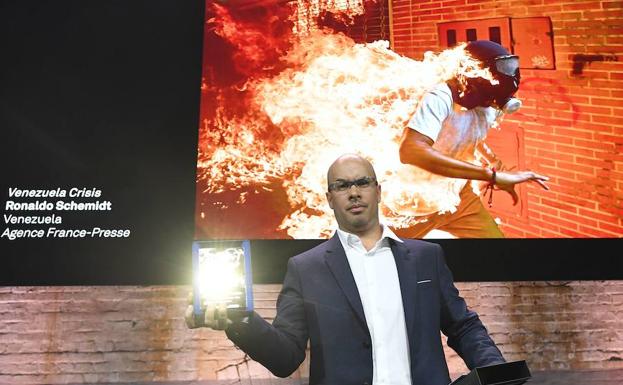 Ronaldo Schemidt posa con su premio delante de la fotofrafía ganadora.