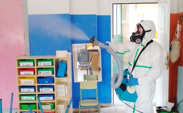 Un trabajador municipal realiza trabajos para desinfectar un aula. 